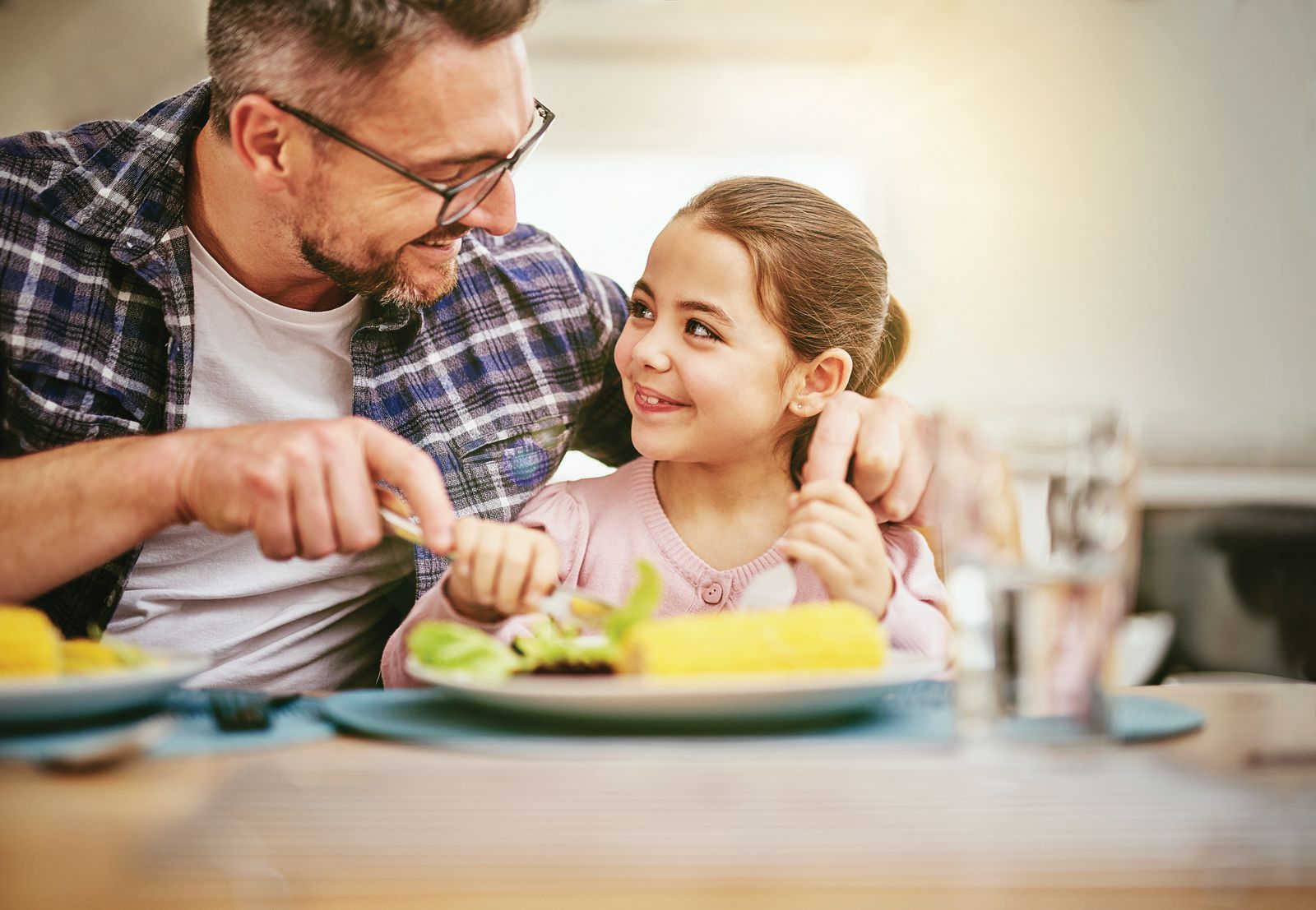 A man and a little girl are sitting at a table eating food.