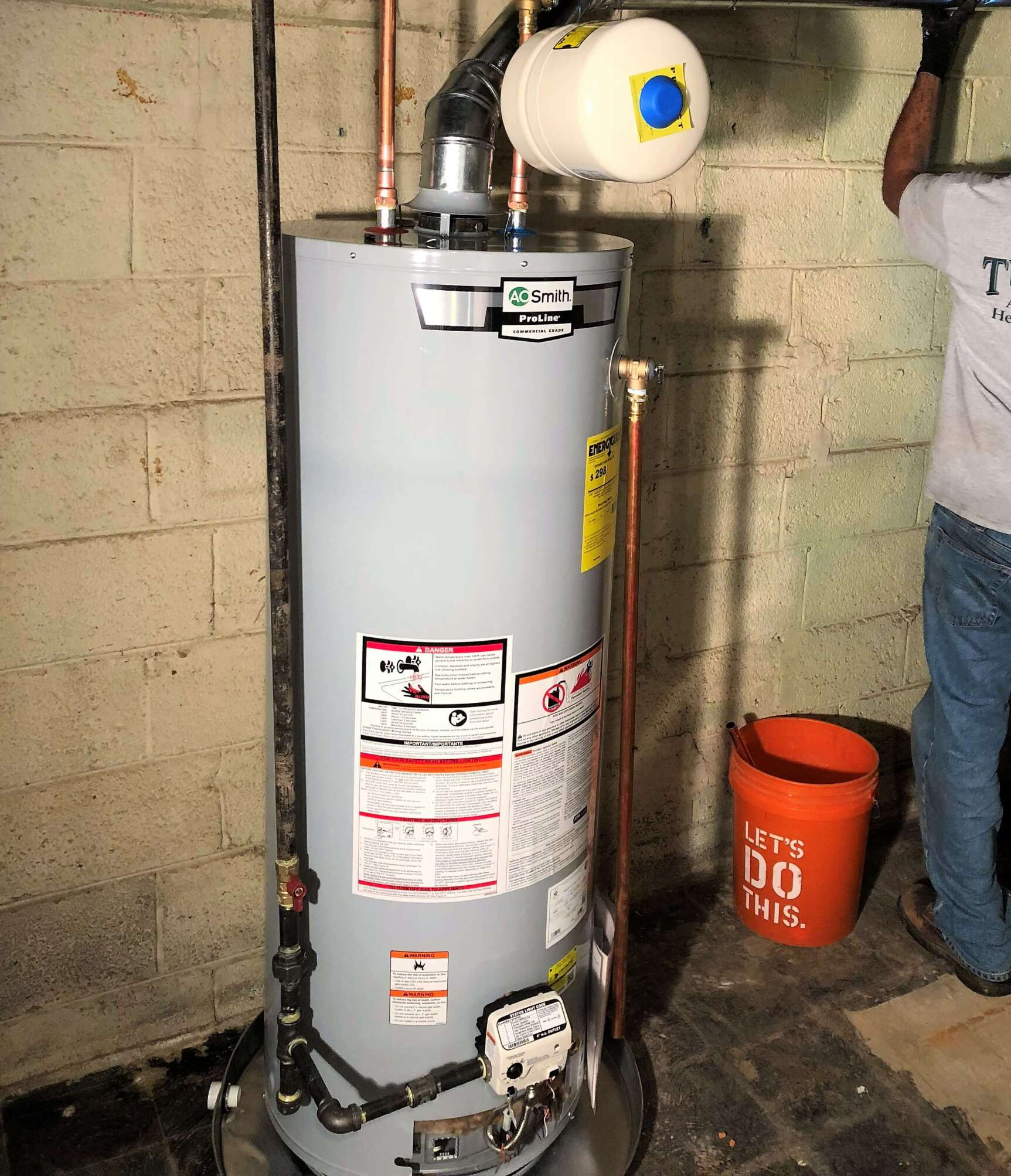 A man is working on a water heater in a basement.