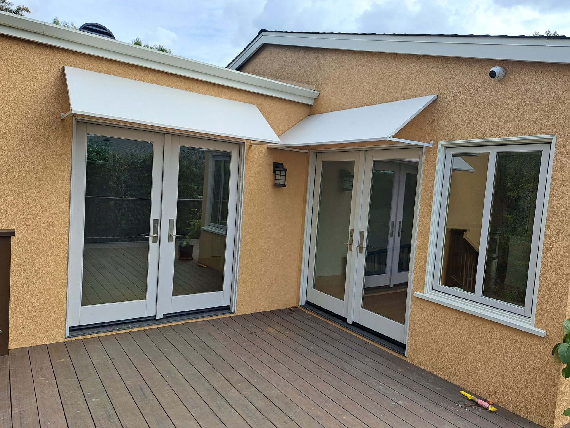 Patio with white French doors, windows, and beige stucco walls under awnings