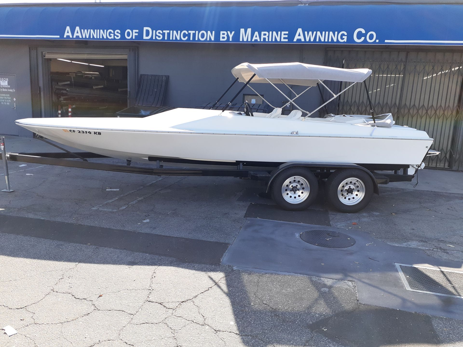 White motorboat on a trailer parked outside a marina awning shop