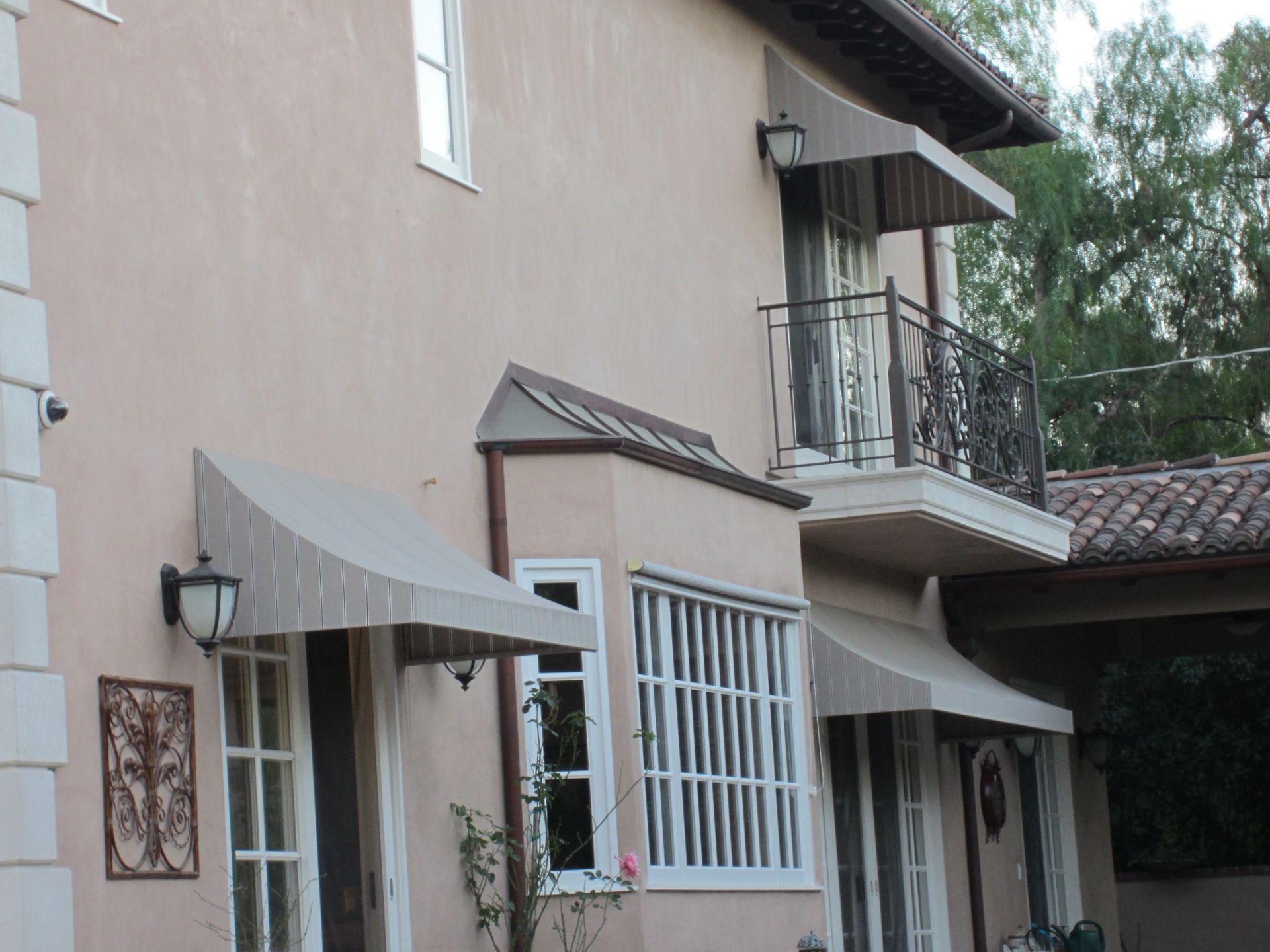 Beige stucco building with windows, balconies, and awnings along a narrow street.