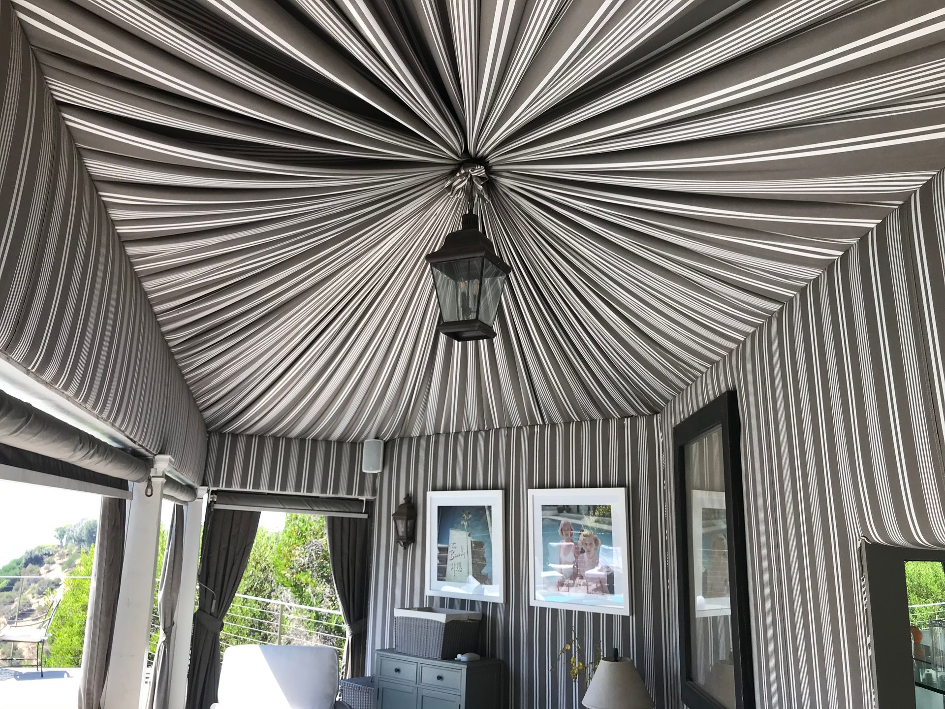 Striped black-and-white pavilion ceiling with hanging lantern and framed art on the walls
