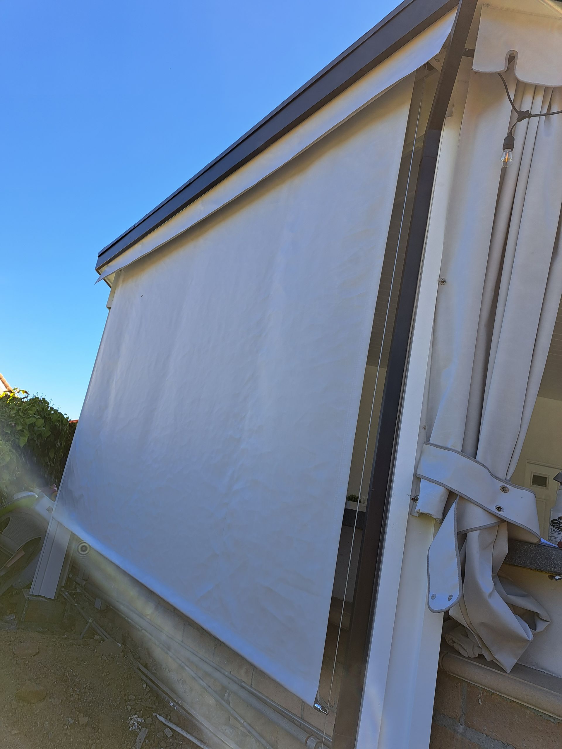 White roller shutter or awning on a building, viewed from an angle against a blue sky