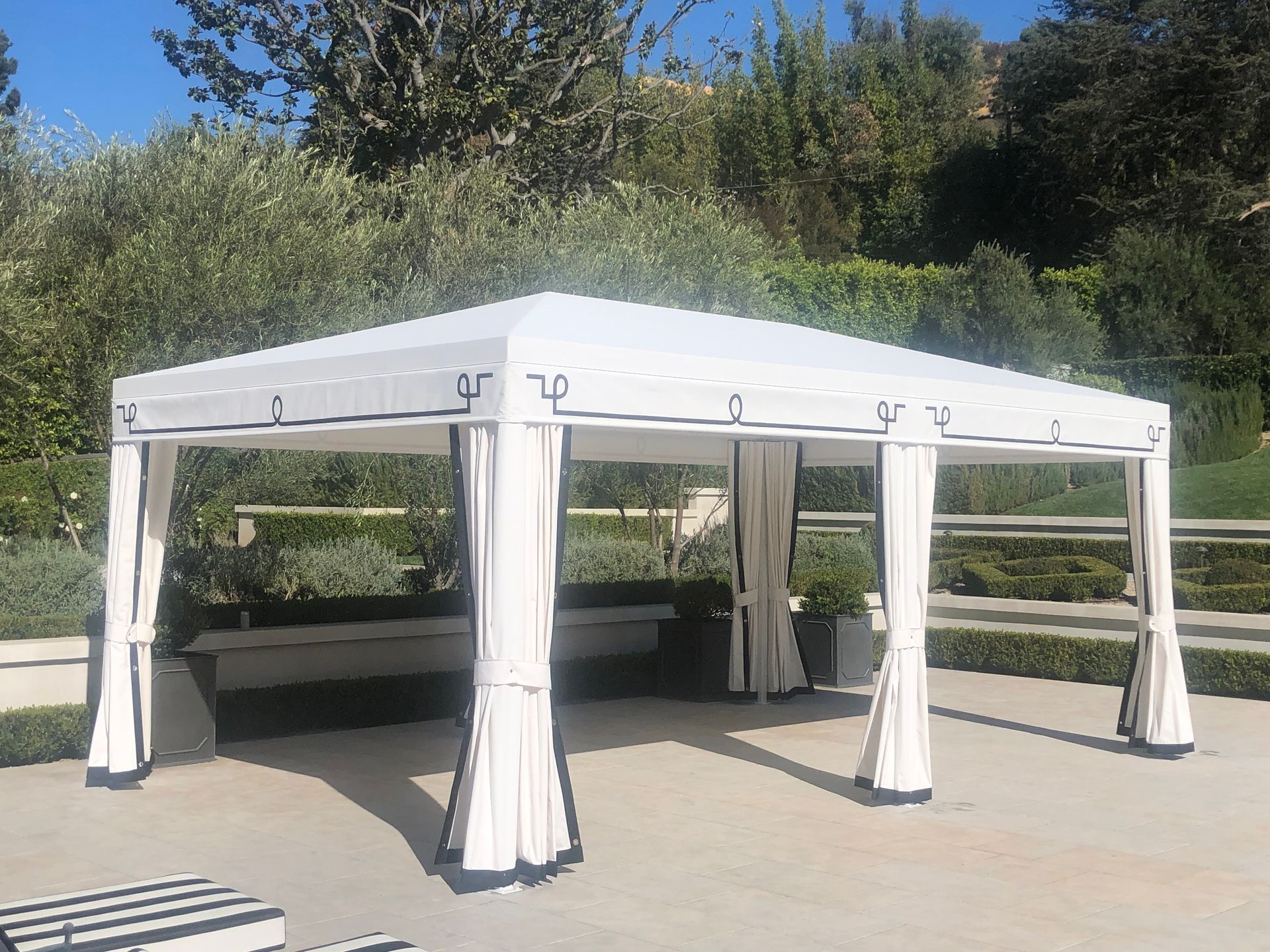 White outdoor canopy tent with curtains in a sunny garden or patio area