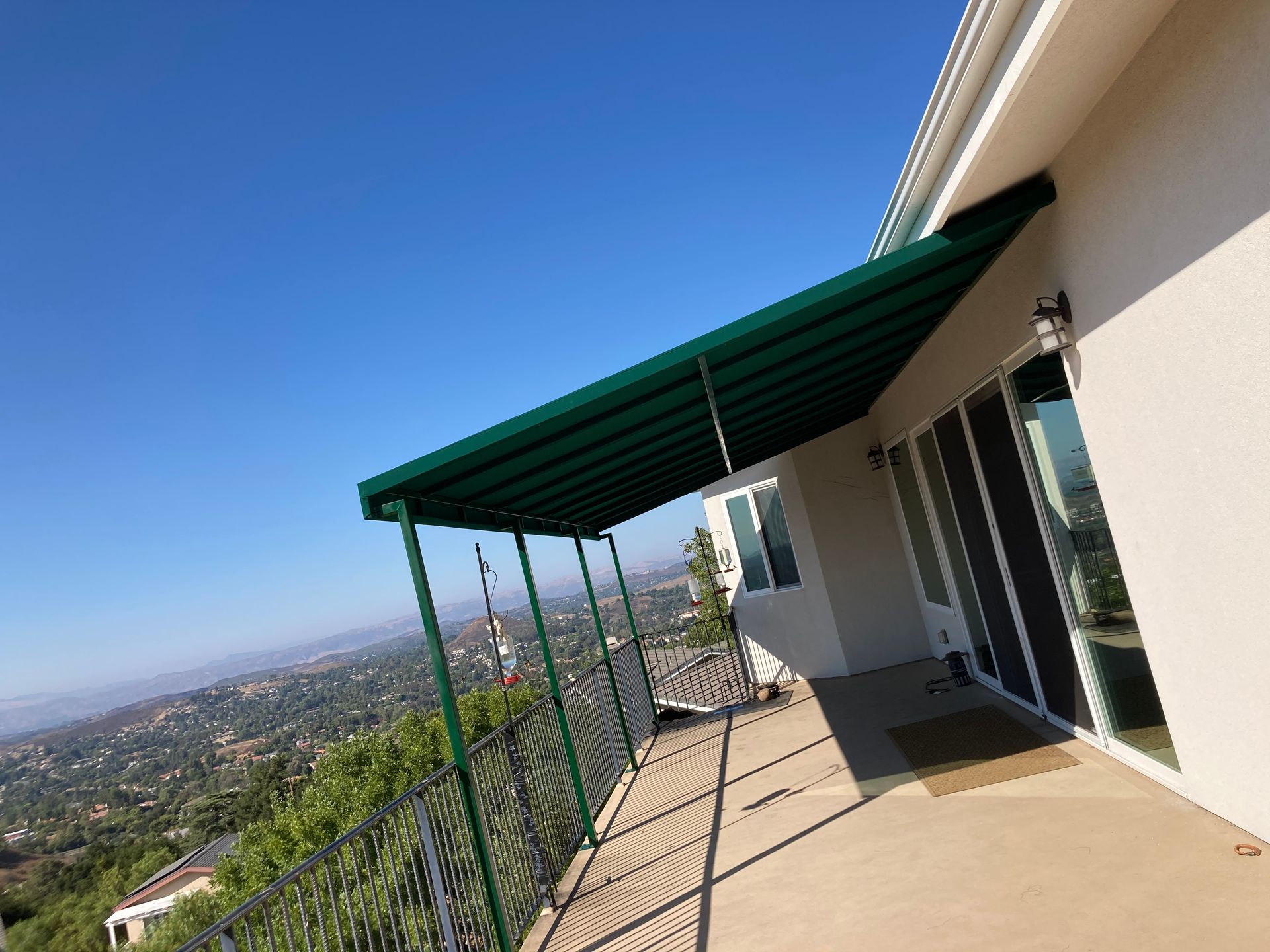 Balcony with green awning overlooking a hillside city view