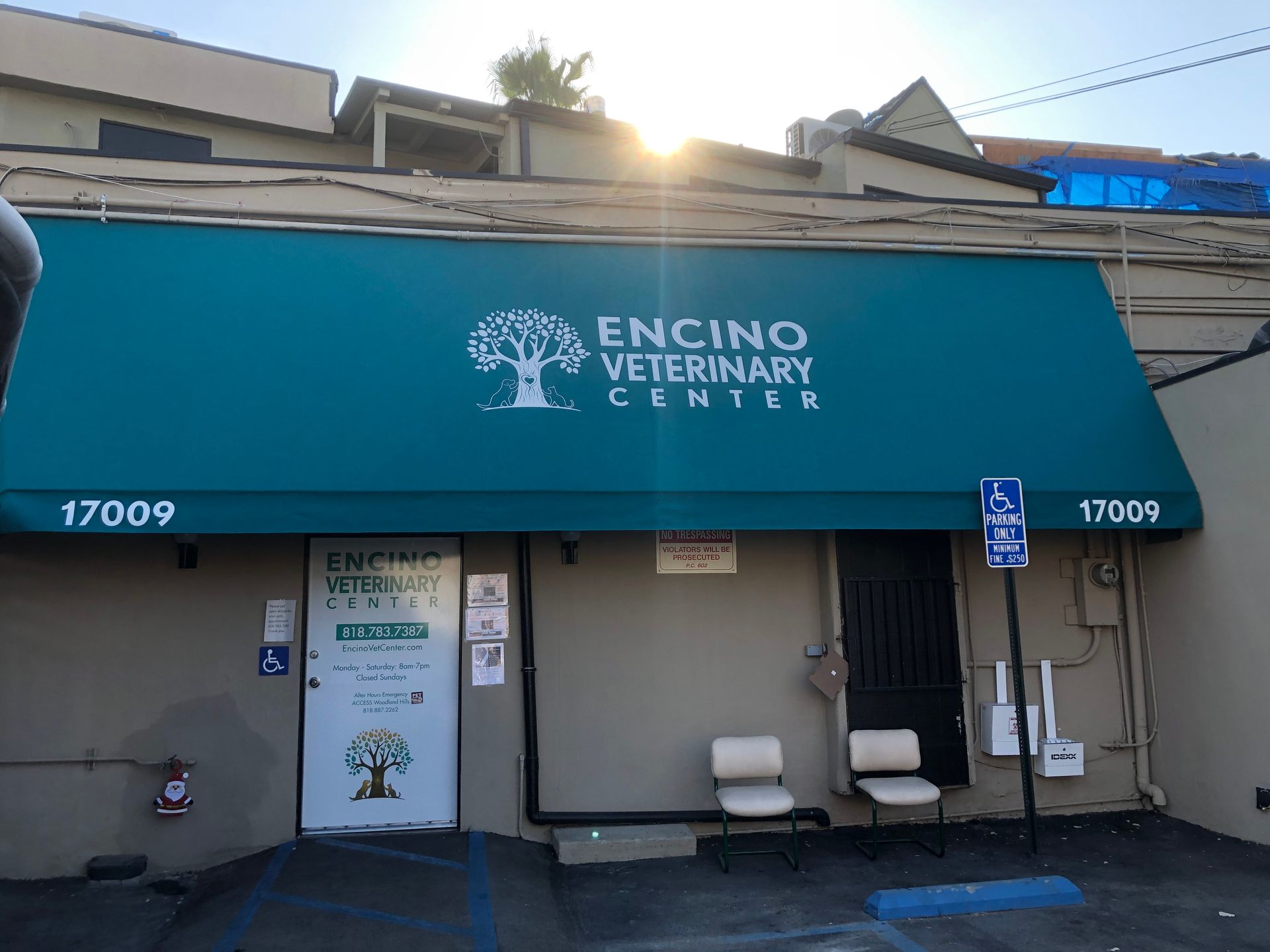 Front entrance of Encino Veterinary Center with teal awning and two white chairs beneath it