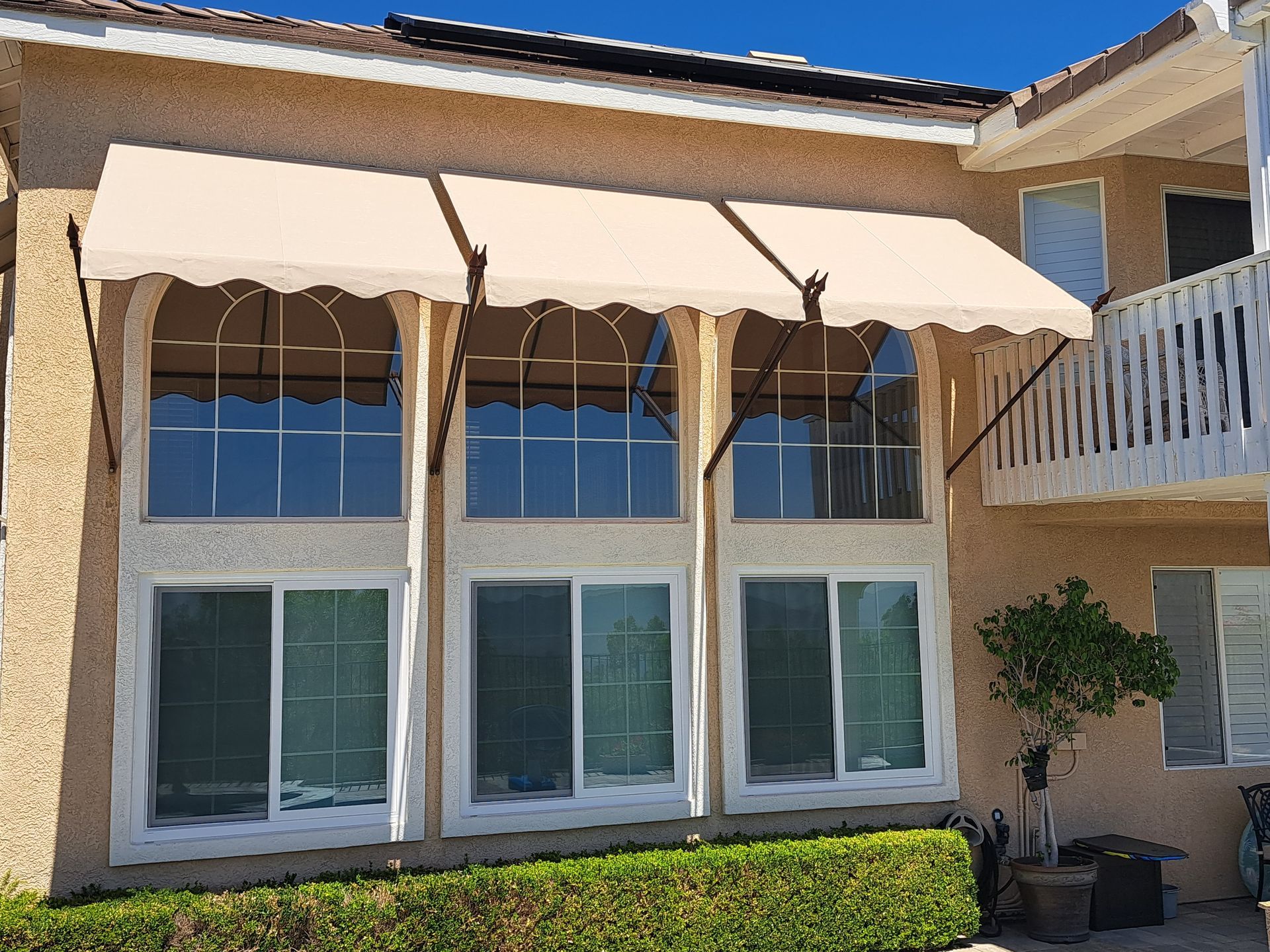 Patio with beige awning over windows and sliding glass doors on a stucco house