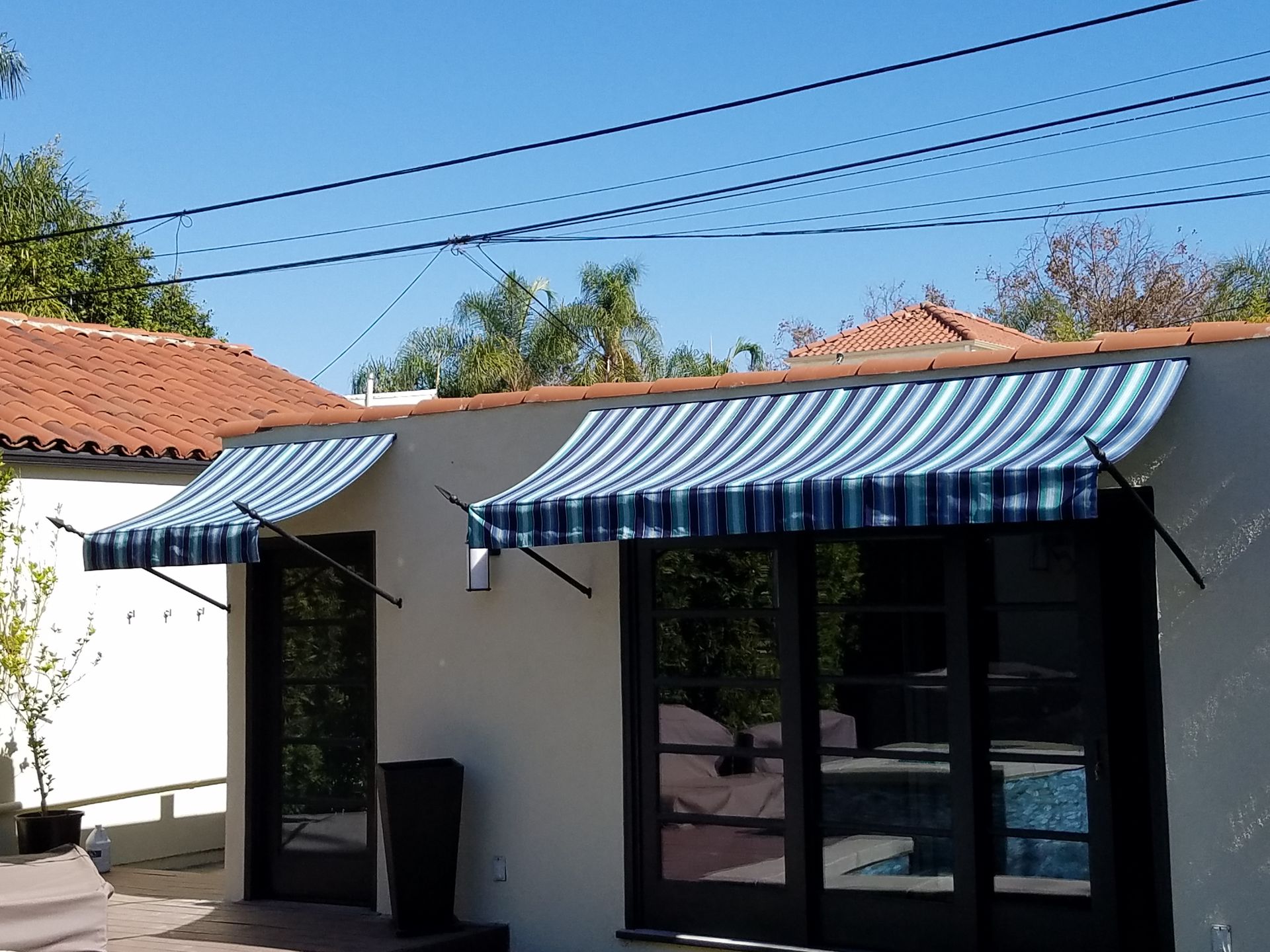Small white building with blue-and-white striped awnings and glass doors under a clear sky