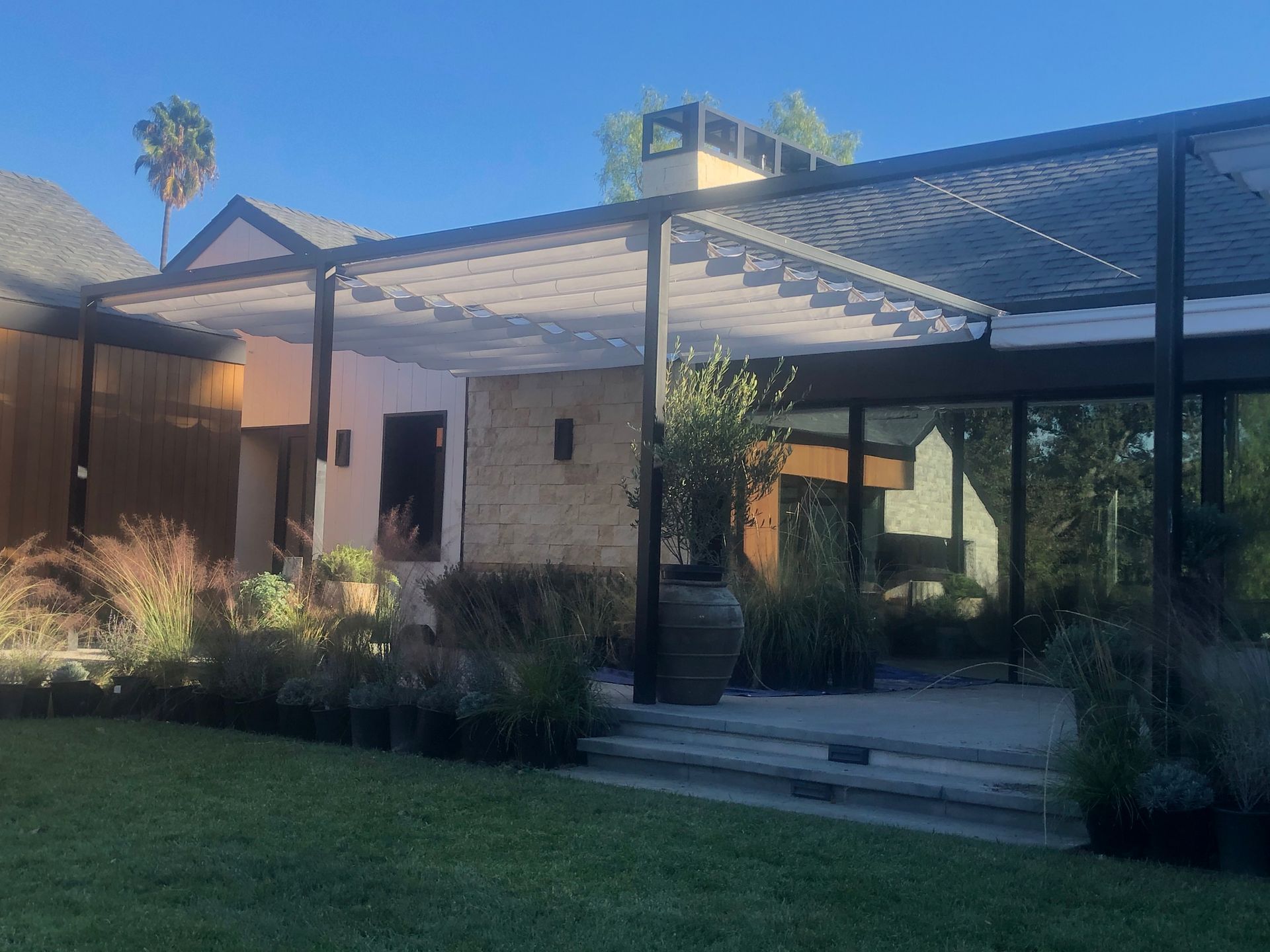 Modern home exterior with a covered patio, glass doors, and a landscaped lawn