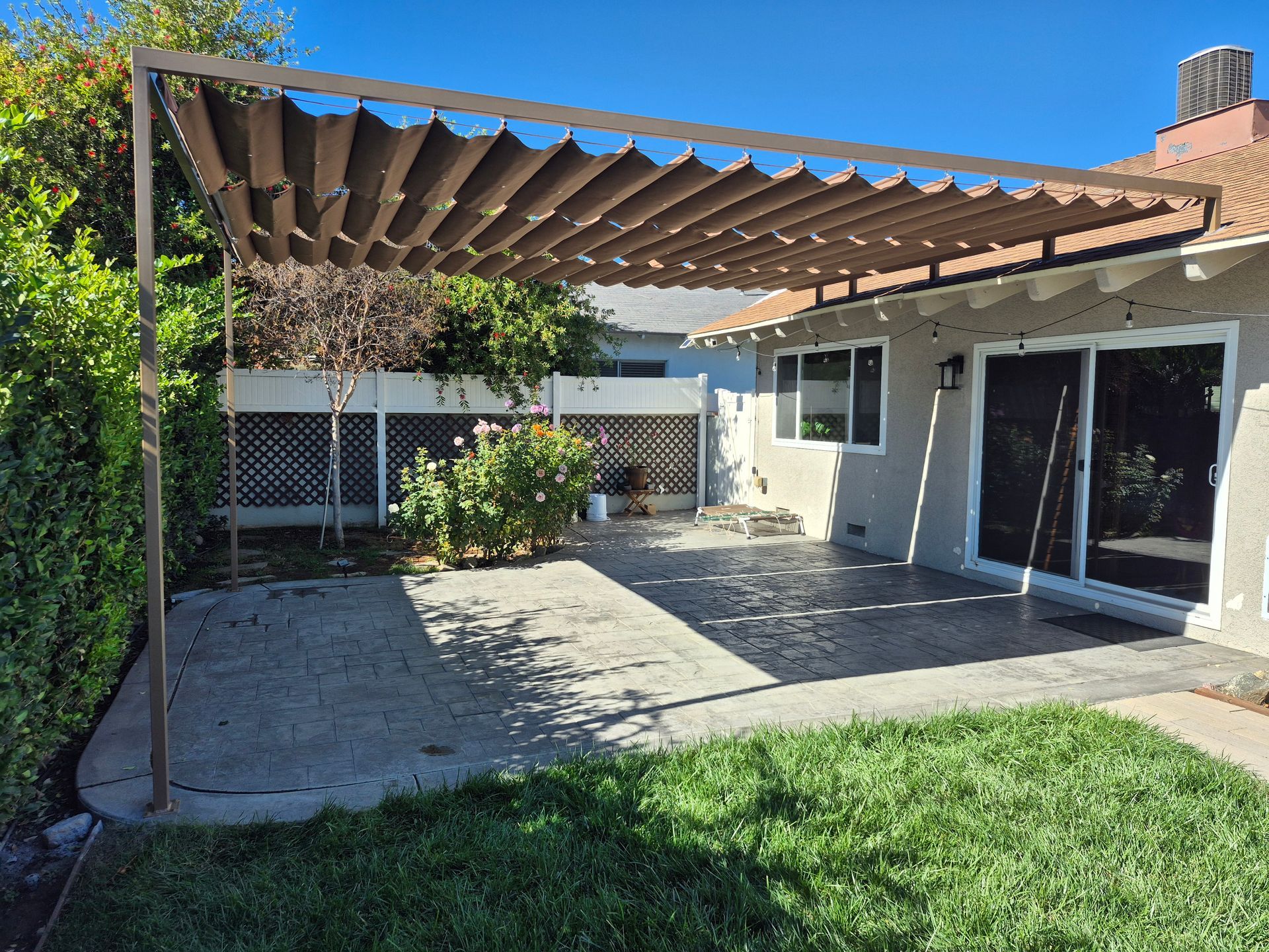 Backyard patio with metal pergola and slide on wire awning panels