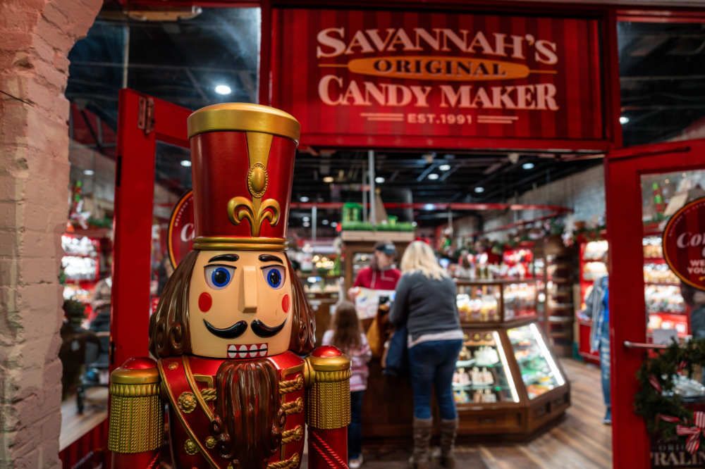 Savannah's Candy Kitchen entrance with a large nutcracker statue and customers inside.