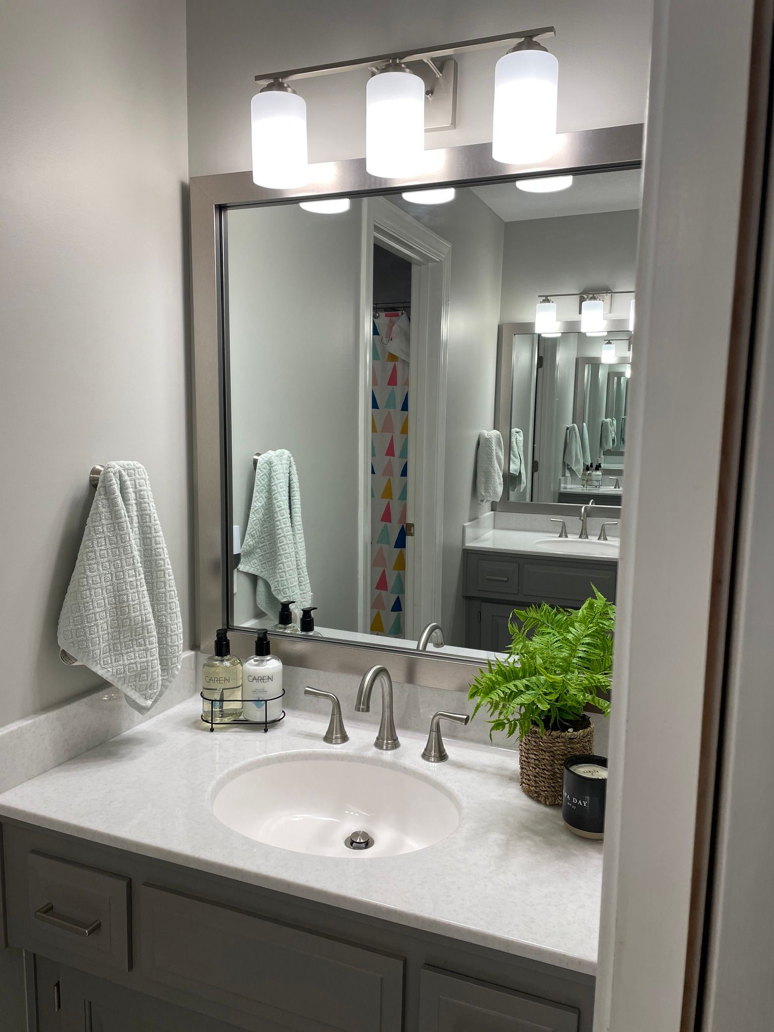 A bathroom with a sink , mirror , and towels.