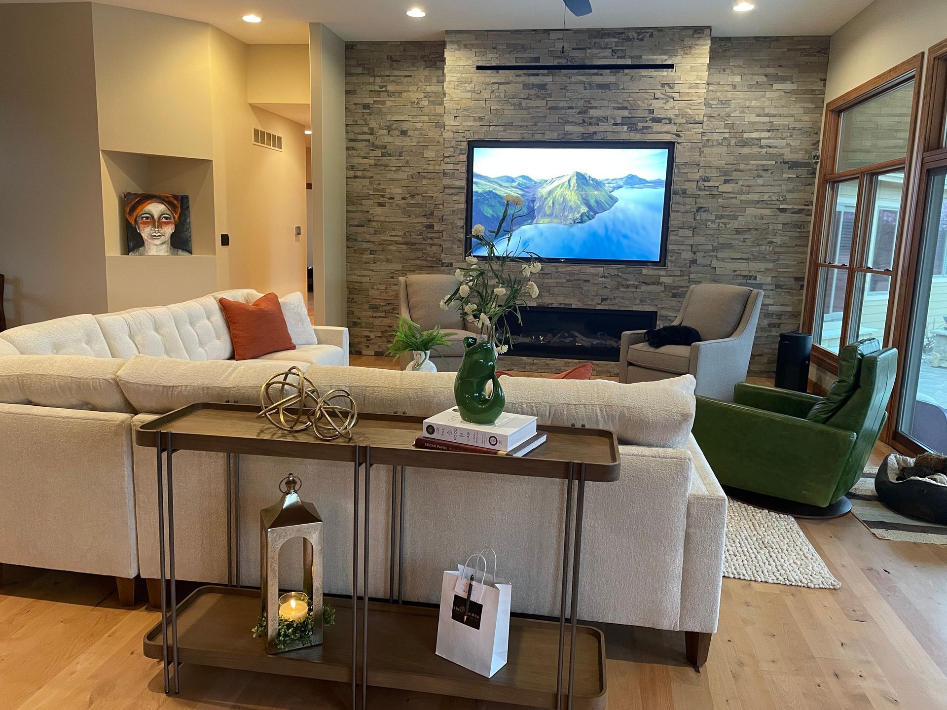 A living room with a large sectional couch and a flat screen tv on the wall.