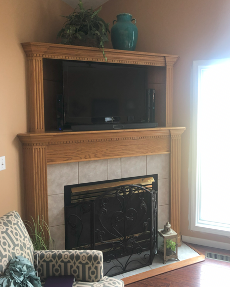 Fireplace with a built-in TV. It is made of wood, and has a tile facade.