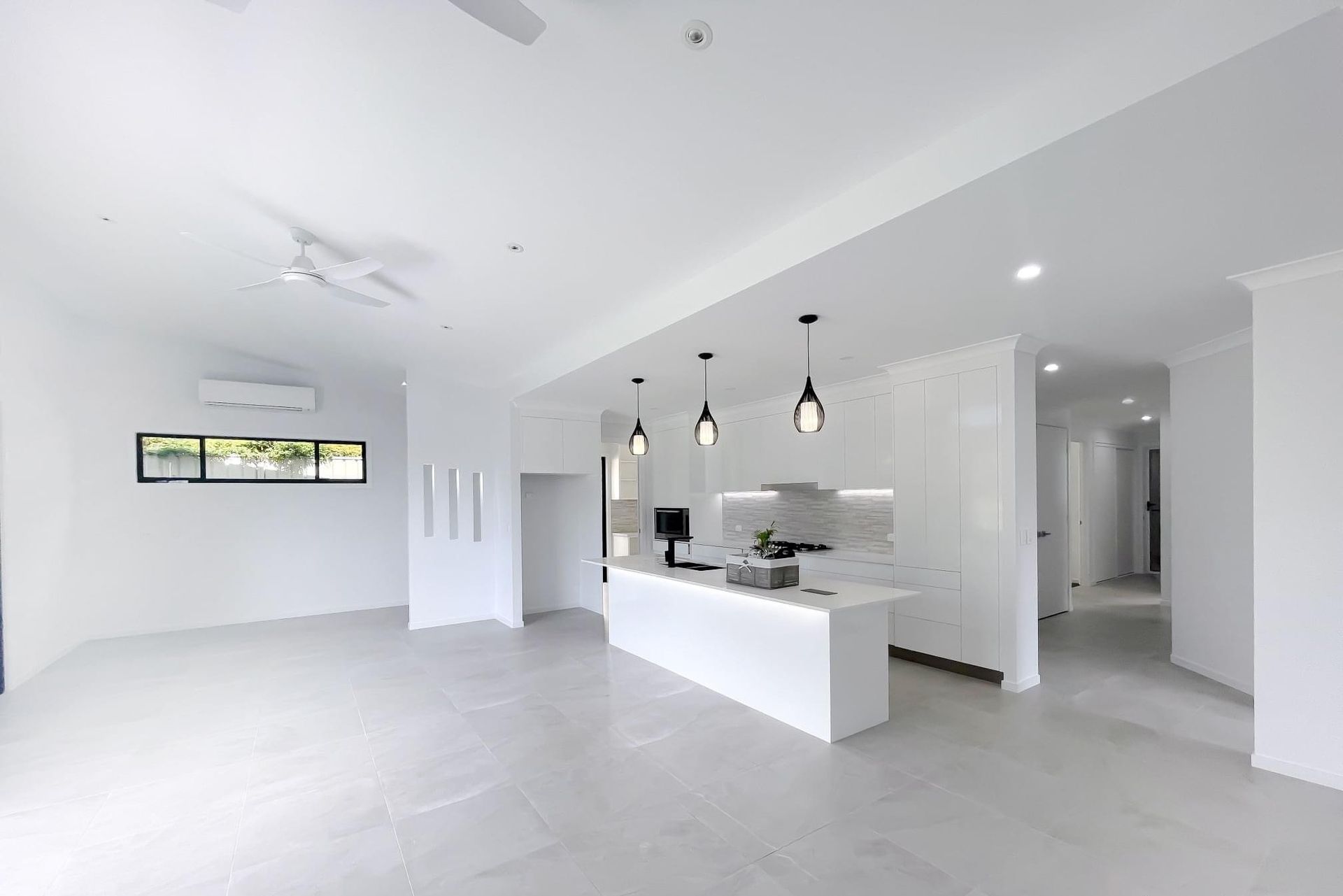 A Large Empty Room With a Kitchen and a Ceiling Fan — Werry Building Services in Boyne Island, QLD