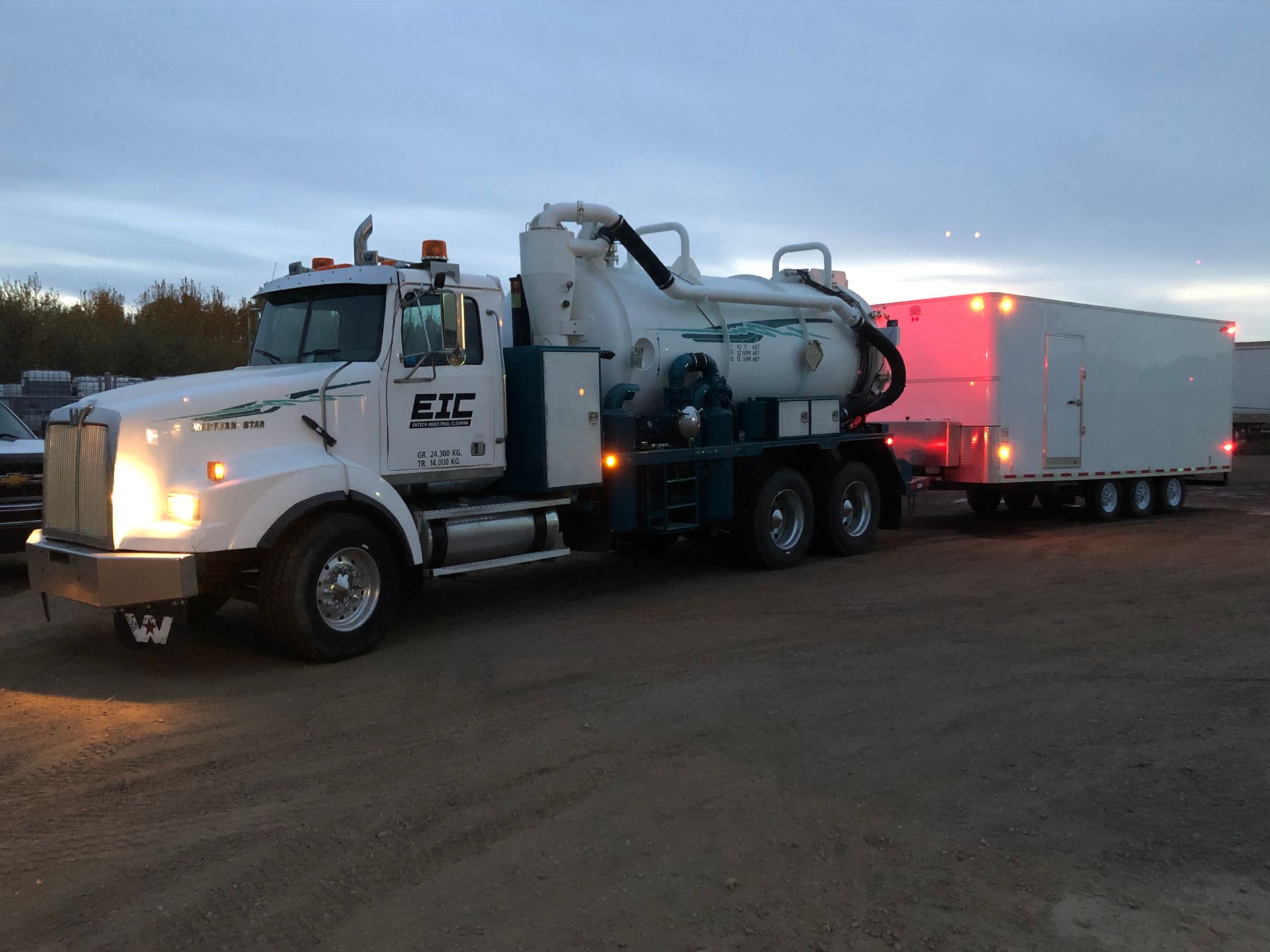A white truck with a trailer attached to it is parked in a parking lot.