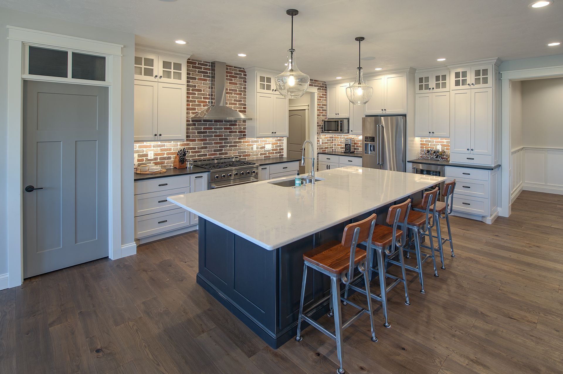 Marble island table with hanging lights near cabinets and a oven.