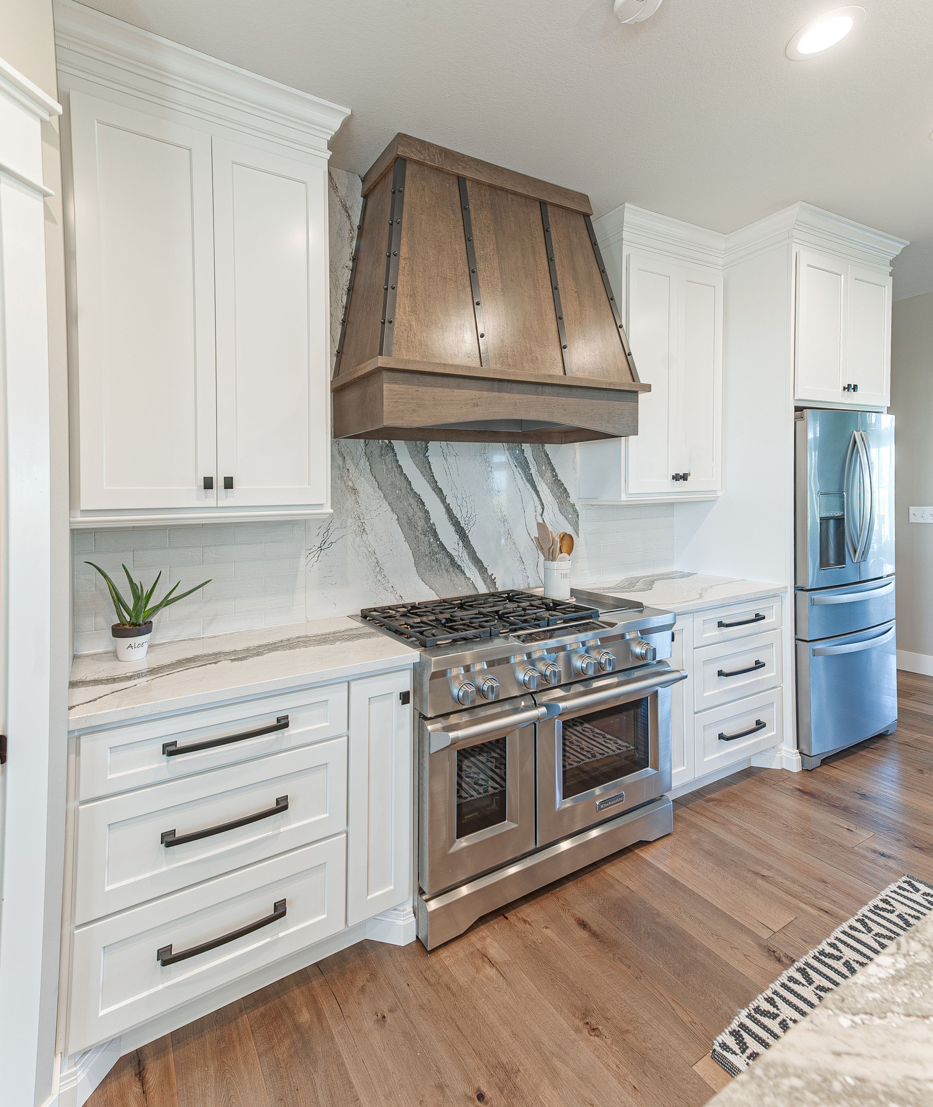 Kitchen wall with a fridge, oven, and cabinets with a marble finish around the stove.