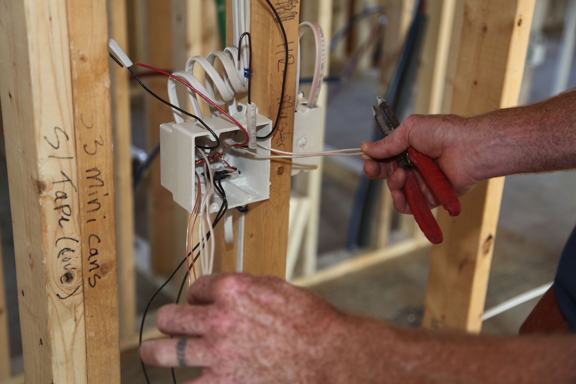 a man is working on an electrical box with a pair of pliers .