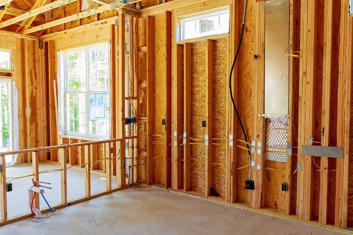 a room in a house under construction with wooden walls and windows .