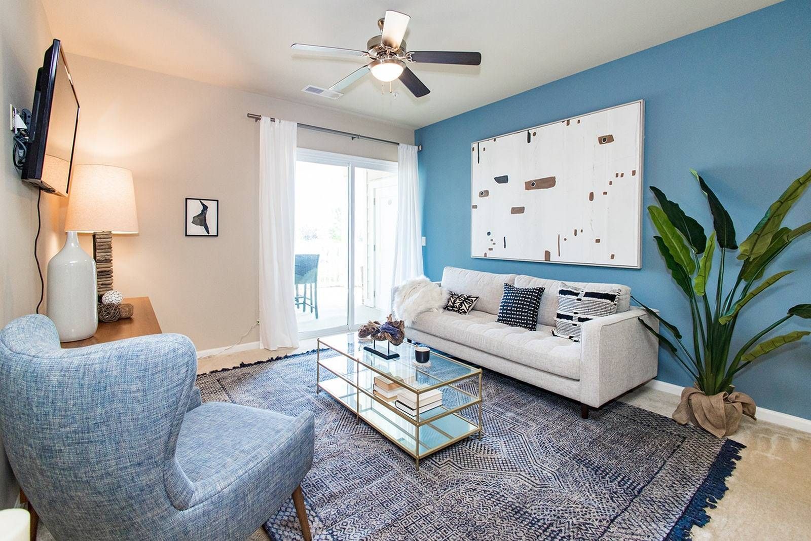 Bright apartment dining area with blue chair, table, kitchen island, and dark cabinets