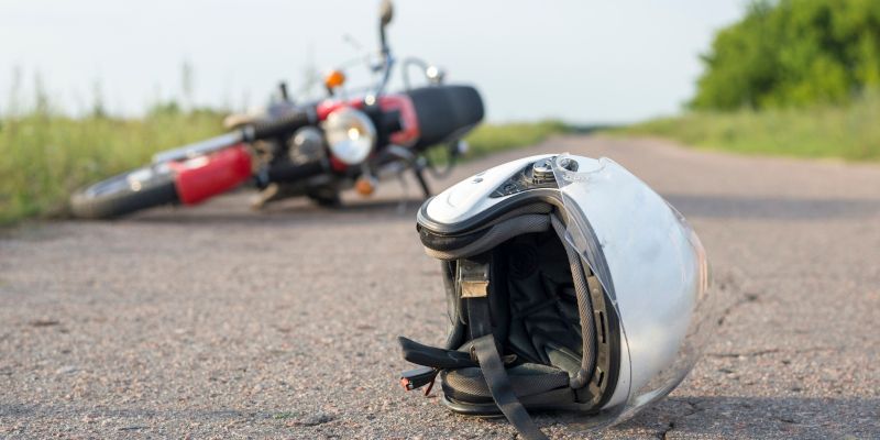 Motorcycle accident on a road; helmet on the ground.