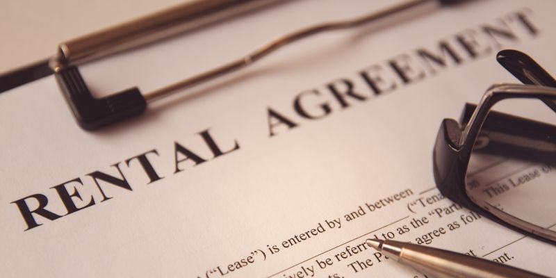 Rental agreement on a clipboard, with glasses and pen resting on it.