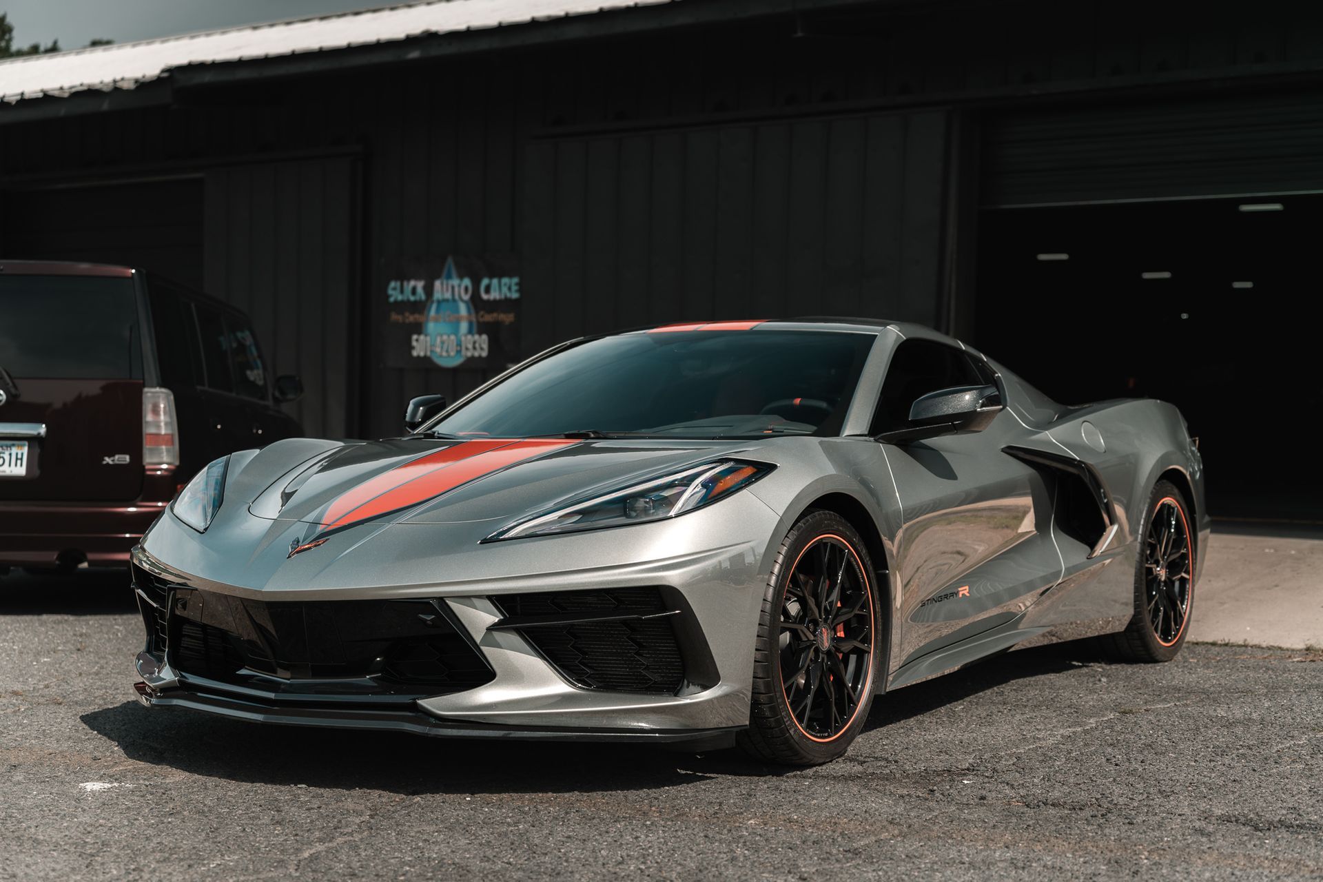 Silver sports car with red accents parked outside a garage