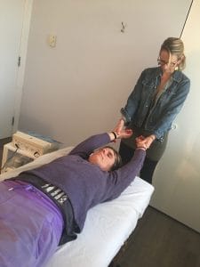 Physical therapist stretching a patient’s arms on a treatment table in a clinic room