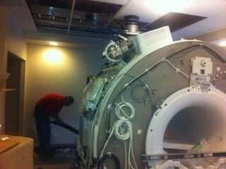 Person bending near a large industrial machine in a dim lab or workshop
