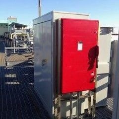 Red industrial electrical control box mounted outdoors on a metal platform