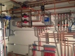 Copper plumbing pipes and manifolds on a wall in a utility room