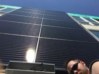 Solar panels on a building with two people in sunglasses at the bottom edge.