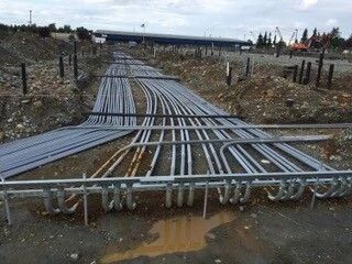 Cable trays and pipes crossing muddy ground at an industrial construction site