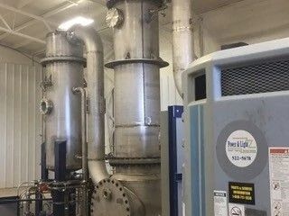 Industrial HVAC room with large silver ductwork and a blue-gray machine unit indoors