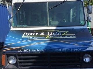 Blue utility truck with “Power & Light” logo on the front grille, parked outdoors