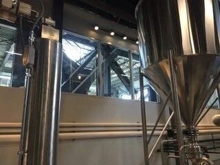 Industrial stainless steel tanks and pipes inside a modern brewery or processing facility.
