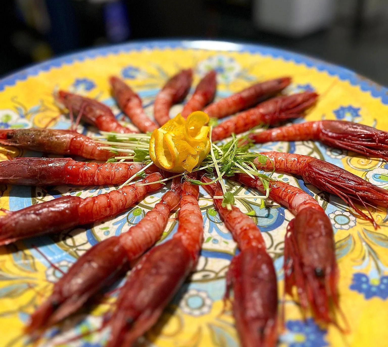 Piatto circolare di salsicce rosse cotte disposte attorno a una guarnizione gialla su un piatto decorato