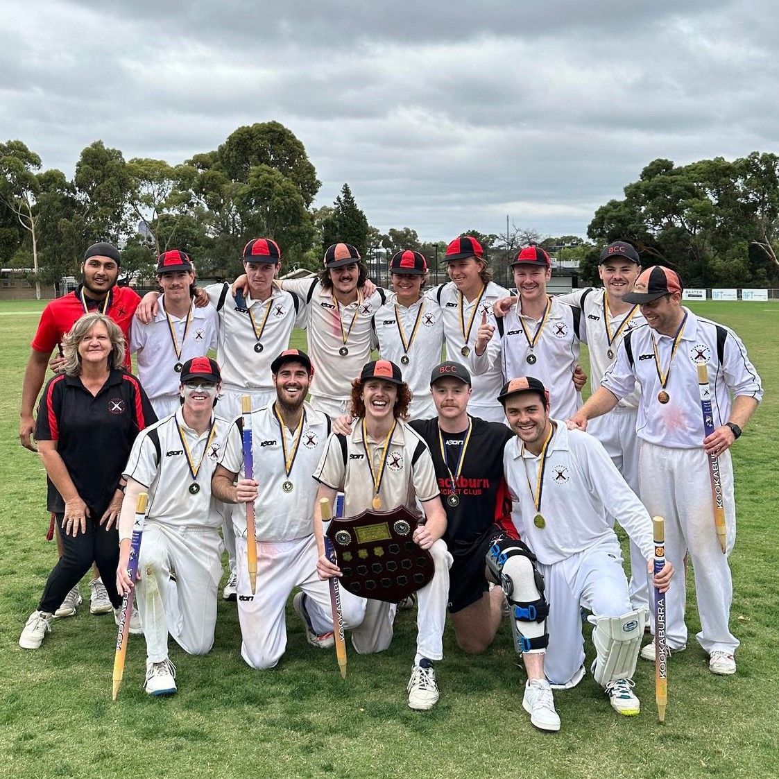 BCC batsman in white raises bat after scoring a century, with teammate beside him on the field