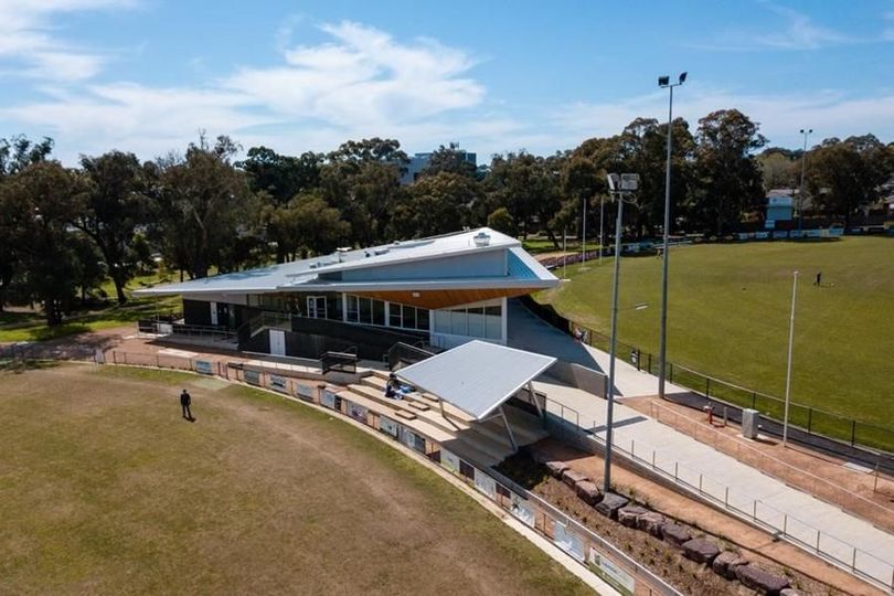 BCC clubrooms and grandstand beside a green sports field (Morton Park) under a blue sky