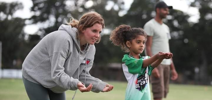 A parent helps a child learn to catch a ball.