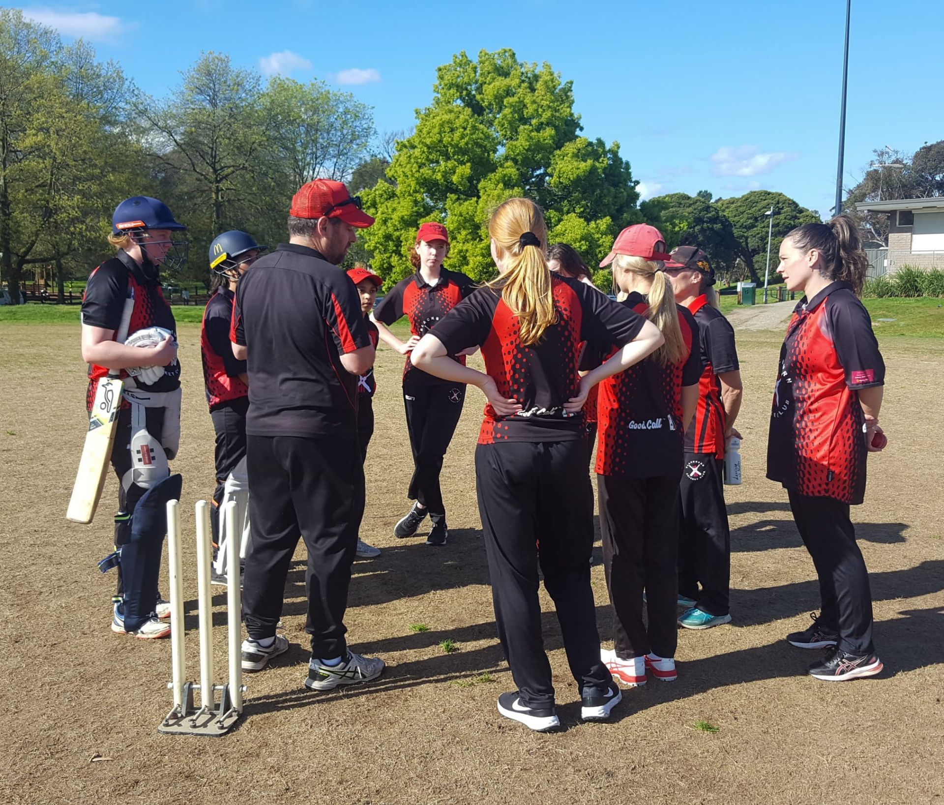 Senior womens team at Blackburn Cricket Club talking to their coach during a match.