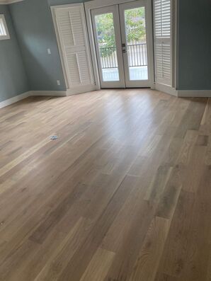 An empty room with hardwood floors and sliding glass doors.