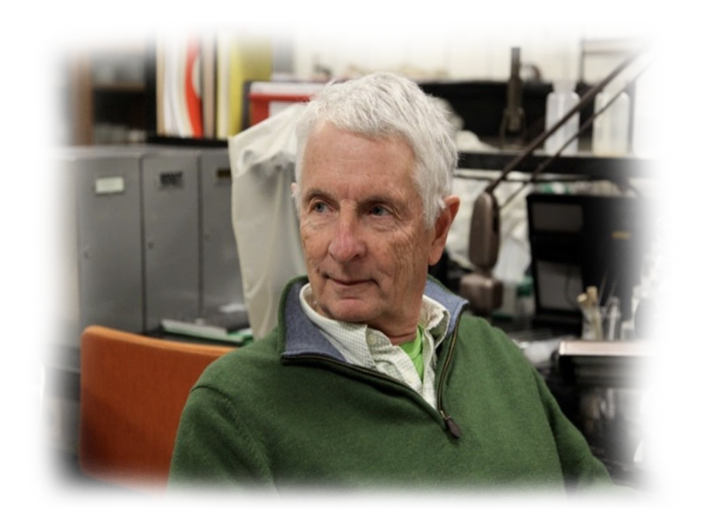 A man in a green sweater sits in front of a microphone