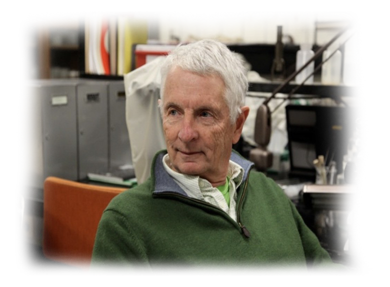 A man in a green sweater sits in front of a microphone