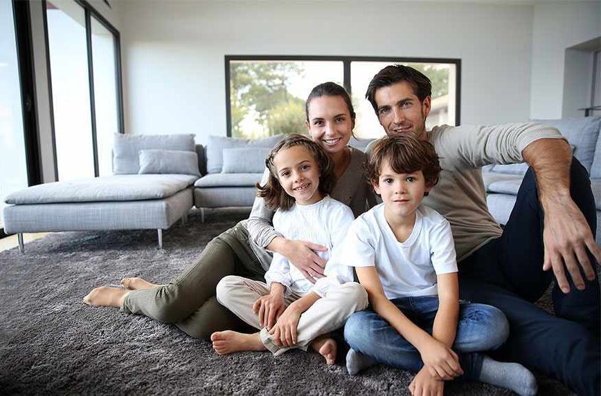 Una familia está sentada en el suelo de una sala de estar.