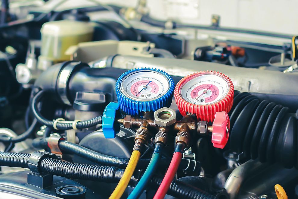 Red and blue manifold gauges connected to hoses on a car engine
