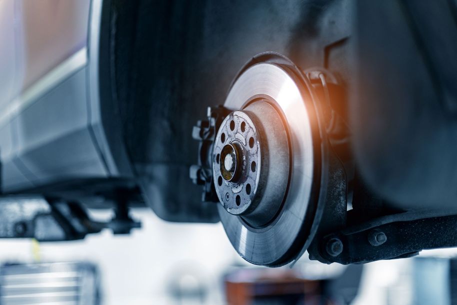 Close-up of a car wheel brake disc and caliper being serviced in a workshop