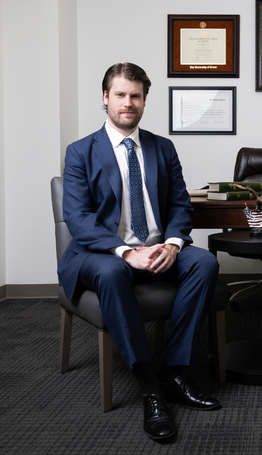 Connor Flanagan sitting in a chair, wearing a suit