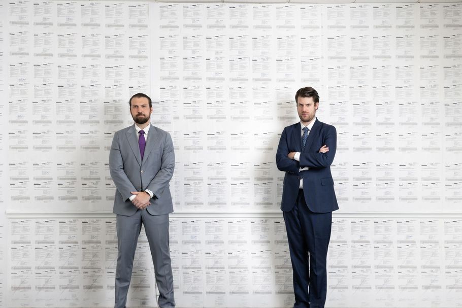 Two attorneys standing in front of a wall, with their arms crossed